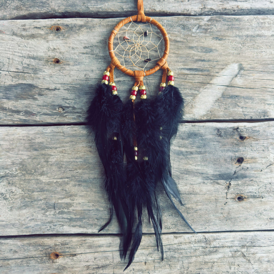 Artisanat autochtone : capteur de rêves de 3 pouces en cuir brun avec perles rouges et dorées, longues plumes noires sur fond de bois gris