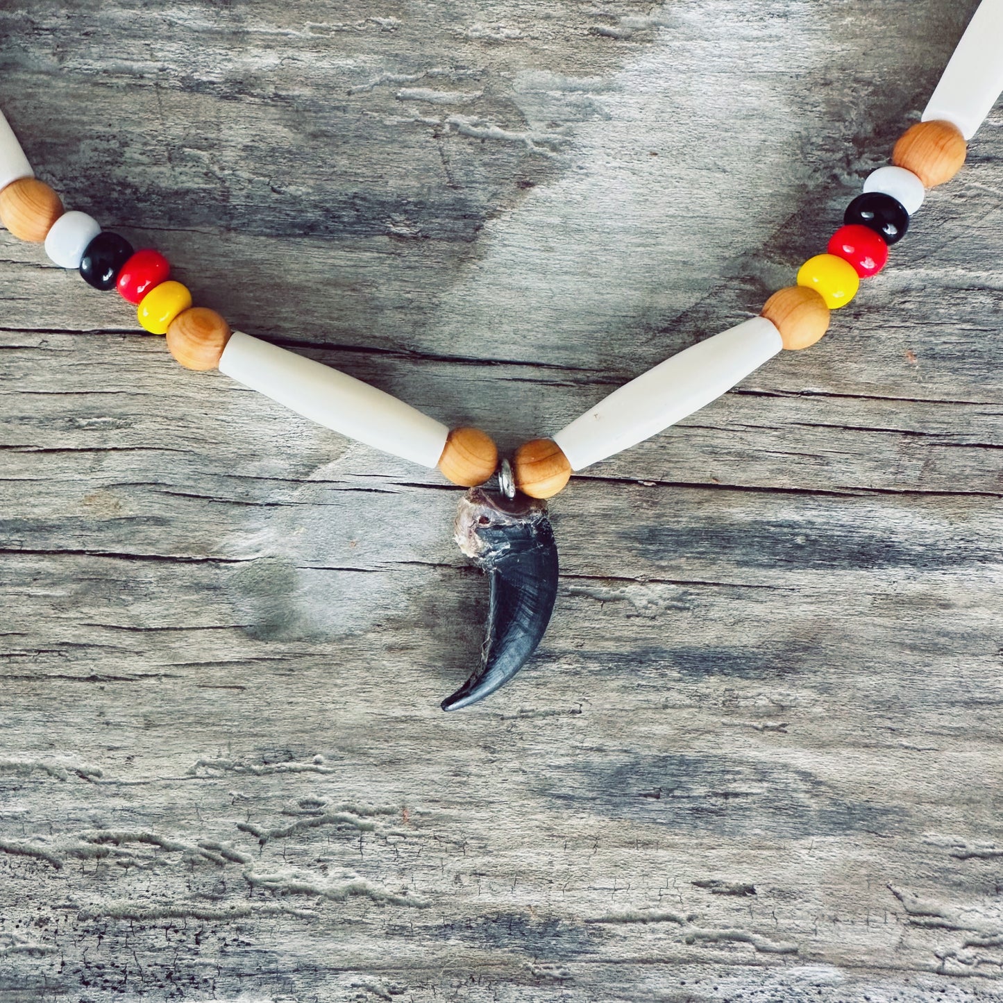Gros plan du bracelet roue de médecine Esprit du Loup montrant la véritable griffe de loup, les perles d'os, les perles de verre et le cuir d'orignal fabriqués à la main par un artisan Ilnu.