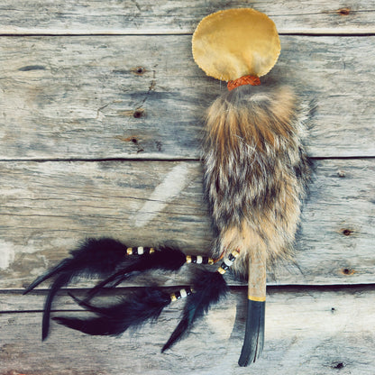 Grand hochet de cérémonie autochtone Gardien du Coyote, fabriqué à la main avec peau de cerf, fourrure de coyote, bois de grève du Piekuakami, cuir d'orignal et plumes naturelles par un artisan Ilnu.