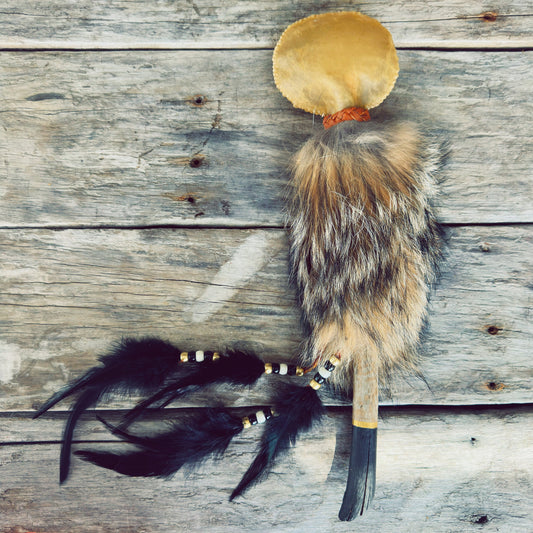 Grand hochet de cérémonie autochtone Gardien du Coyote, fabriqué à la main avec peau de cerf, fourrure de coyote, bois de grève du Piekuakami, cuir d'orignal et plumes naturelles par un artisan Ilnu.