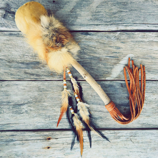 Hochet spirituel autochtone en fourrure de renard, fabriqué à la main par un artisan Ilnu avec peau de cerf et matériaux naturels.