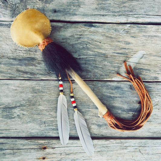 Hochet traditionnel autochtone en fourrure d'ours noir avec plumes d'oie sauvage, fabriqué à la main par un artisan Ilnu de Mashteuiatsh.