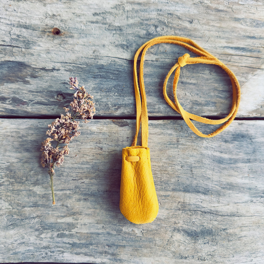 Sac de médecine artisanal en cuir d'orignal naturel beige avec cordon ajustable, incluant une pierre semi-précieuse et de la sauge, créé par l'artisan Ilnu Dave Verreault-Thisselmagan.