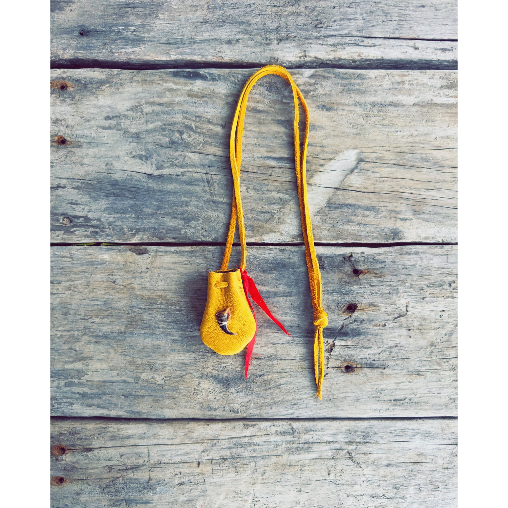 sac de medecine en cuir d’orignal avec griffe de loup sur planche de bois